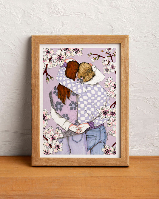 Two women embrace beneath a flowering almond tree, surrounded by branches and delicate blossoms, illustrated print by Ana Jarén