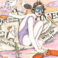 Une femme en maillot et lunettes de plongée voyage sur un bateau géant en papier journal, entourée d’oiseaux marins et de bouées, œuvre originale d’Ana Jarén.