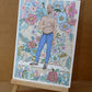 Un homme torse nu pose parmi de grandes fleurs et des fragments d’ornements classiques, œuvre originale d’Ana Jarén.